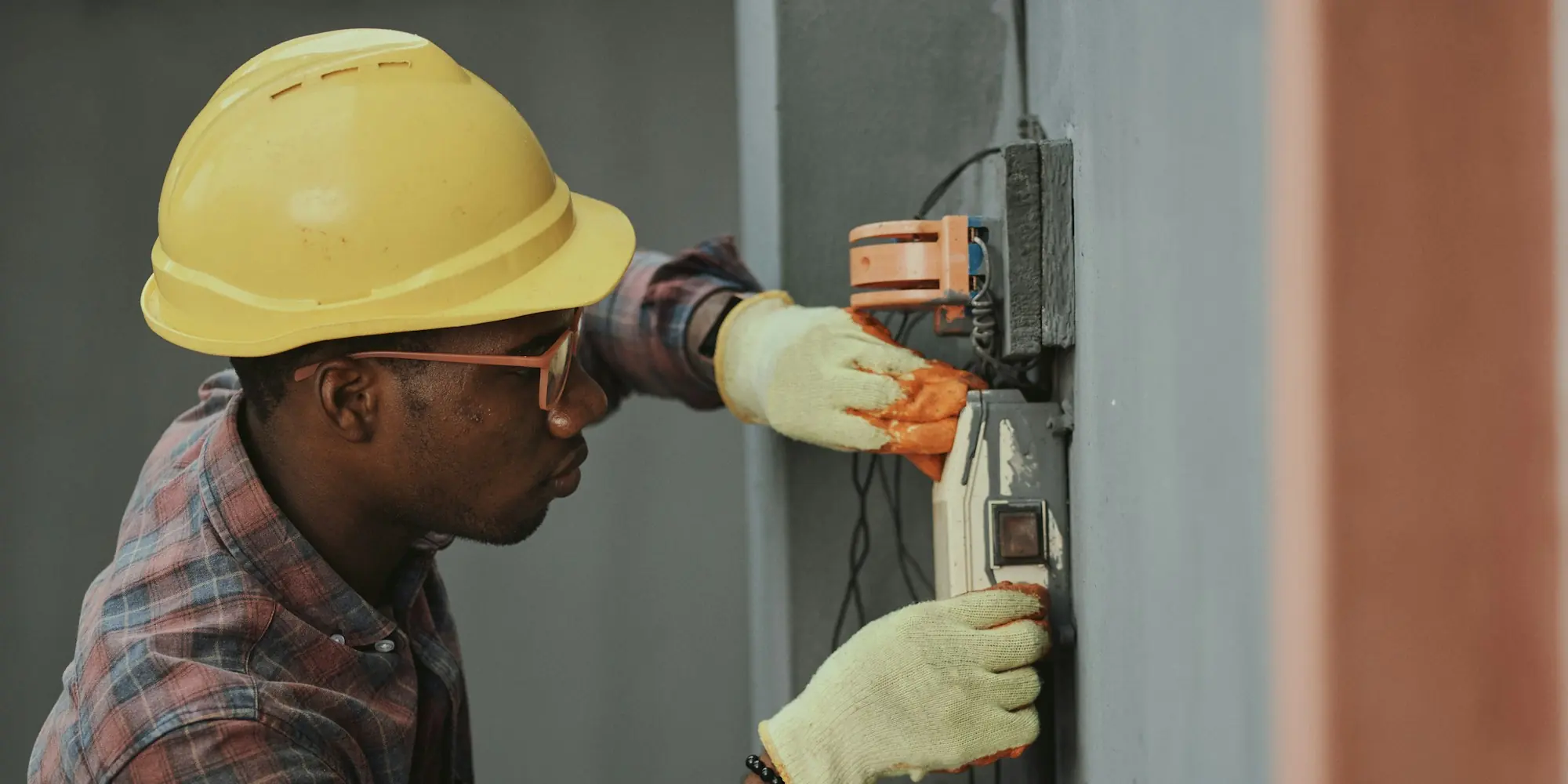 Electrician in a yellow hard hat installing wiring