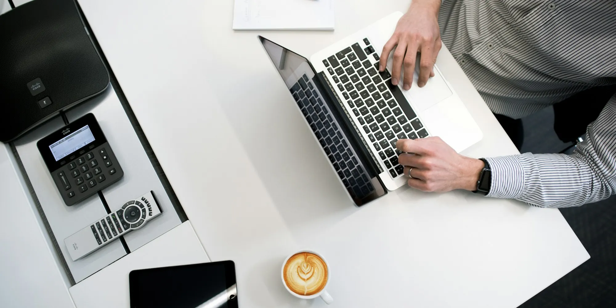 Business owner using a laptop at a white wooden table