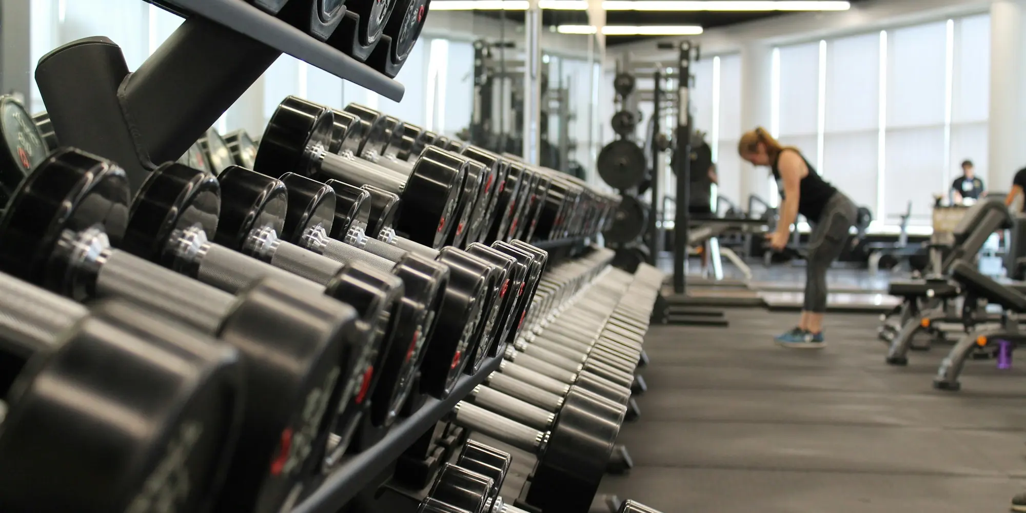 Woman training in a gym surrounded by racks of weights