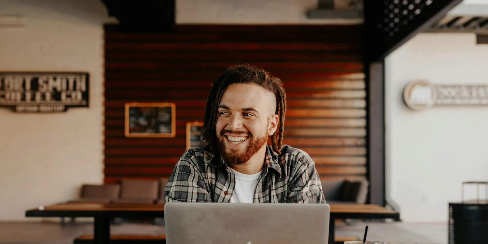 Smiling business owner working on a laptop at a table in his shop
