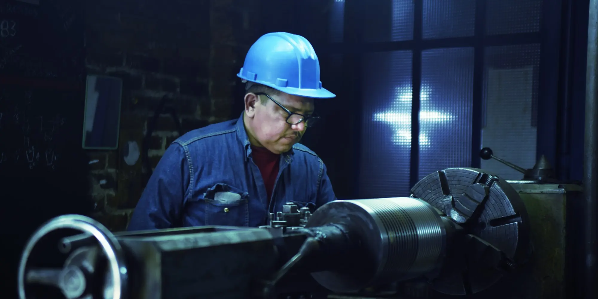 Machinist in a hard hat working at a lathe