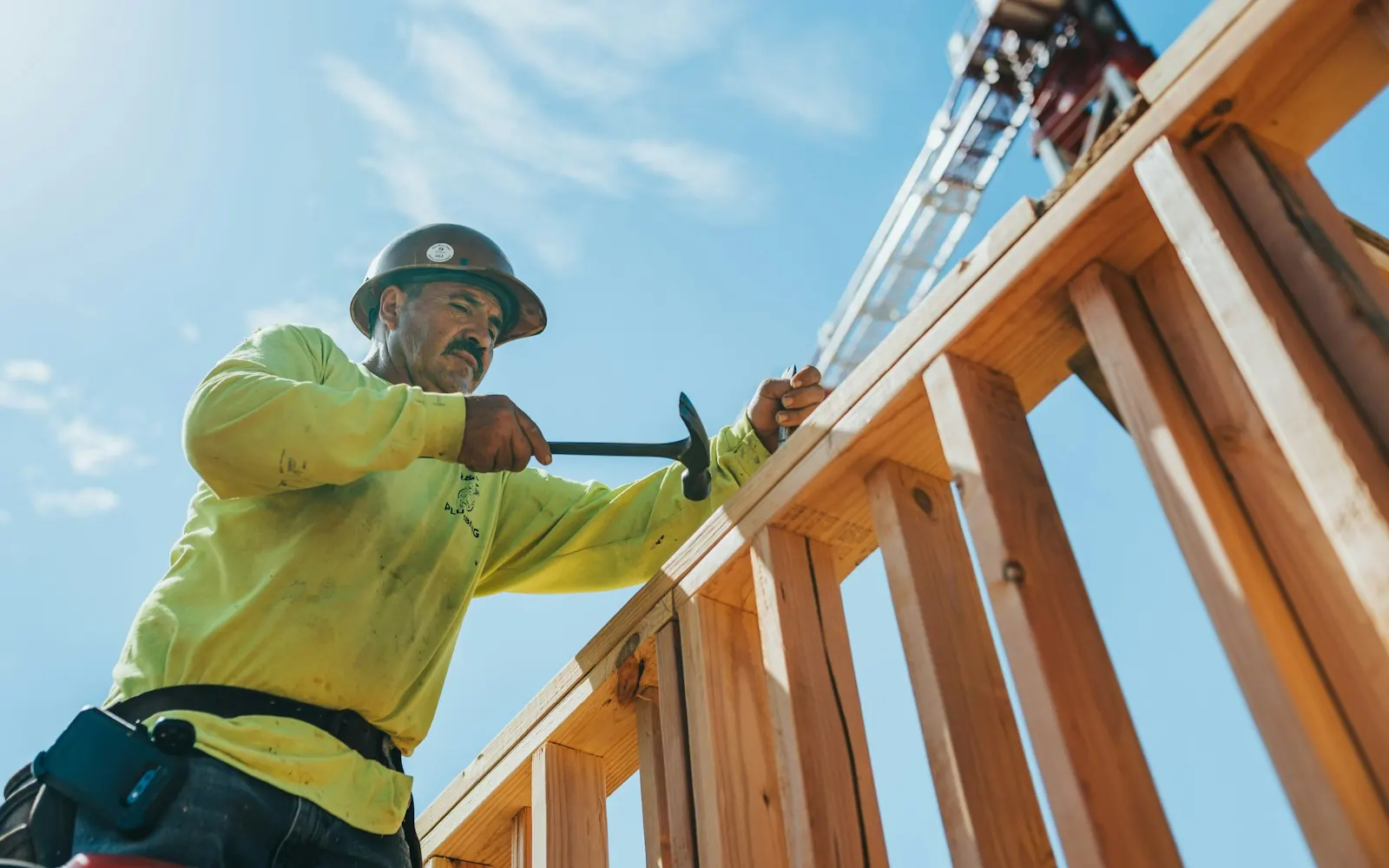 Construction worker in a hard hat framing a wooden structure on a job site