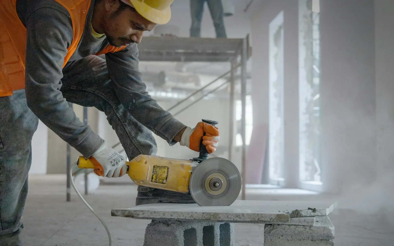 Construction worker cutting concrete with an angle grinder on a job site