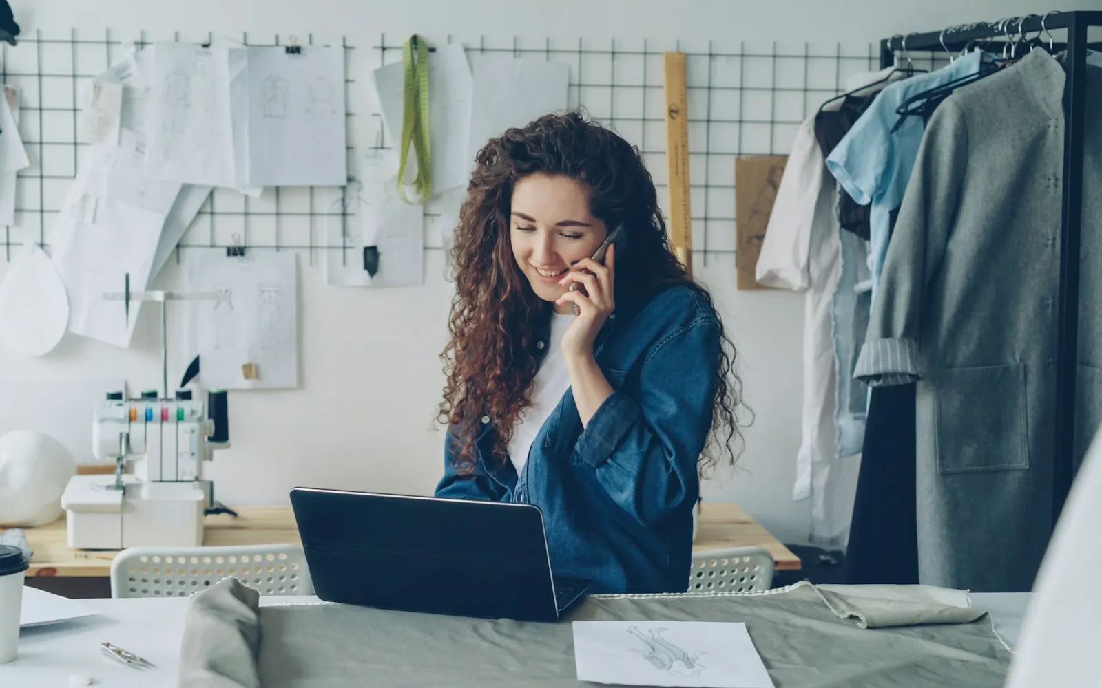 Small business owner on the phone at her laptop in her studio, talking through a funding offer