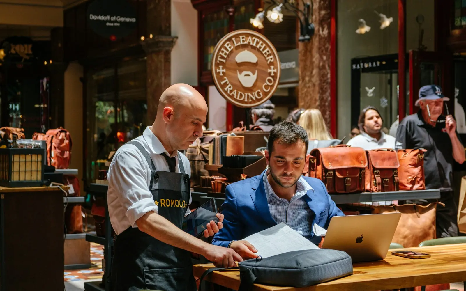 Shop owner and a customer going over paperwork on a laptop in a store